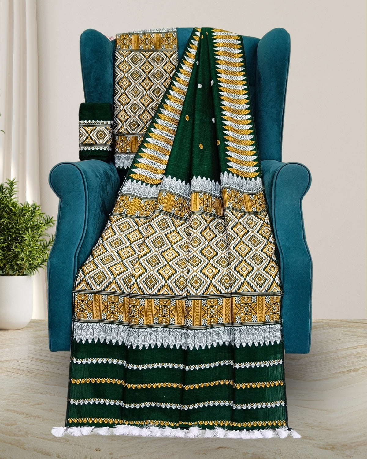 A green and yellow padmini cotton mekhela chadar with designer motifs displayed on a blue armchair.