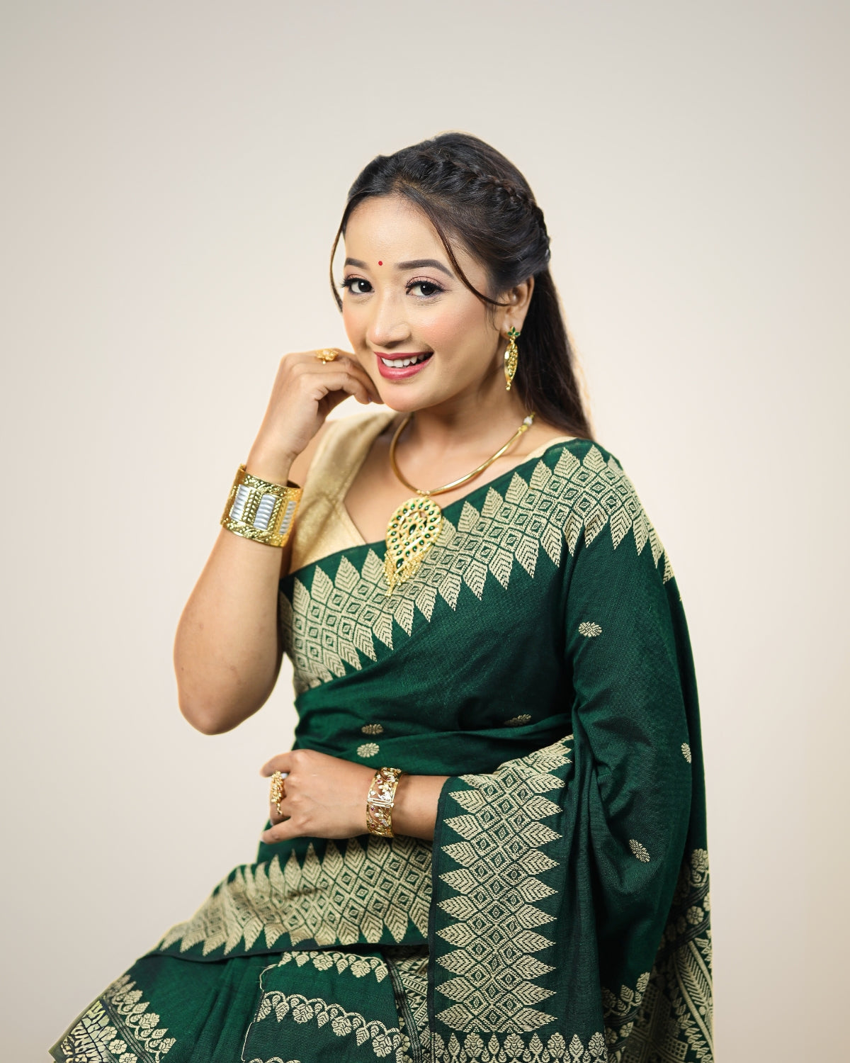 Woman wearing a green and gray patterned mekhela sador on a white background