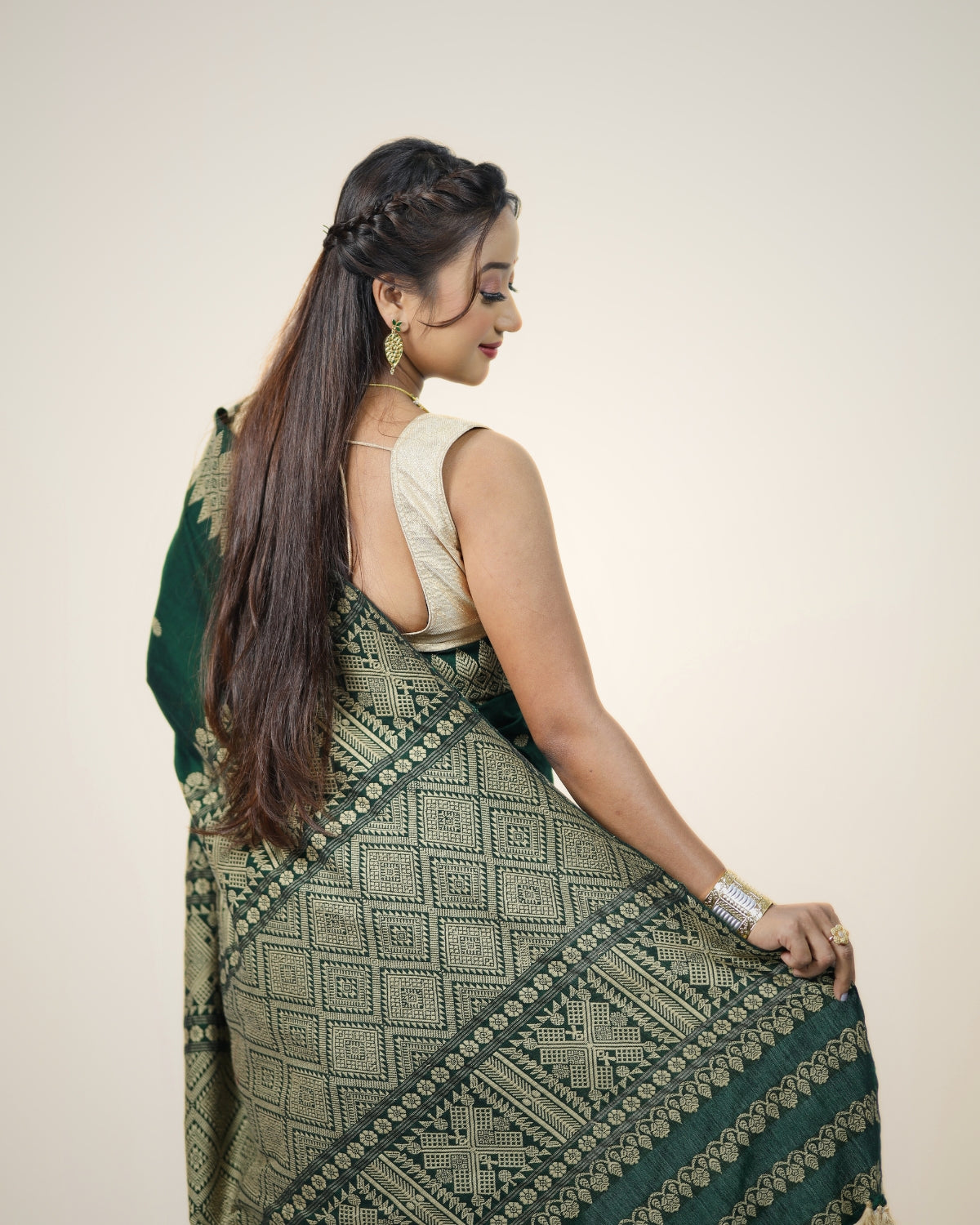 Woman wearing a green and gray patterned mekhela sador on a white background